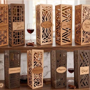 Op de afbeelding: Een collectie rechthoekige houten geschenkdozen voor wijnflessen met ingewikkelde lasergesneden patronen en houten plaatjes met gegraveerde teksten zoals Congratulations, For You, Thank You, With Love en Cheers in diverse houttinten.