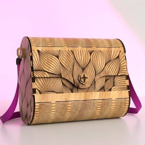 Peut inclure: Un sac à main rectangulaire en bois présentant un motif découpé au laser composé de lignes courbes et fluides sur le rabat avant et les côtés. Le sac possède un fermoir circulaire en bois au centre et une bandoulière en tissu violet vif.