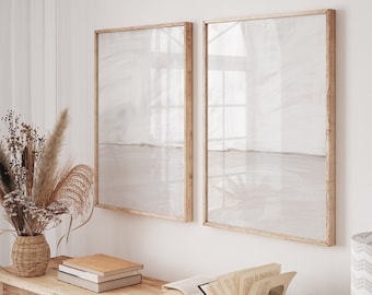 Può includere: Un tavolo console in legno con una finitura in legno chiaro. Il tavolo ha due ripiani ed è decorato con un vaso di fiori secchi, libri e una ciotola decorativa. Due stampe incorniciate con uno sfondo beige chiaro sono appese al muro dietro il tavolo.