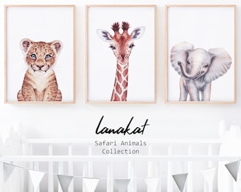 Puede incluir: Tres pinturas de acuarela enmarcadas de animales de safari: un cachorro de león, una jirafa y un elefante. Los marcos son de madera clara y el fondo es blanco. El texto "lanakat Safari Animals Collection" está debajo de los marcos.