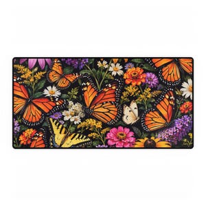 May include: A rectangular desk mat featuring a vibrant botanical pattern on a black background. The design includes multiple orange and black monarch butterflies, a yellow swallowtail butterfly, and various colorful flowers.