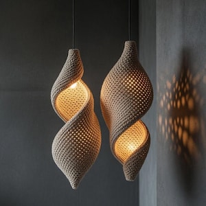 Può includere: Due lampade a sospensione beige a forma di spirale sono appese a cavi neri contro un muro grigio. Le luci sono realizzate in un materiale tessuto, con un bagliore caldo che emana dall'interno. Il design crea un'estetica unica e strutturata.