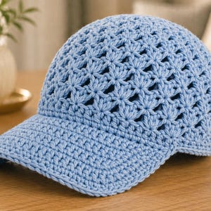 Puede incluir: Gorra de béisbol de ganchillo azul claro con un patrón floral. La gorra tiene una visera curva y un diseño de tejido abierto. El sombrero está hecho de hilo suave y es adecuado para climas cálidos.
