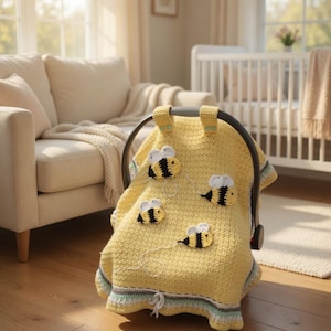 Puede incluir: Una funda de asiento de coche para bebé de ganchillo amarillo adornada con cuatro abejas aplicadas. La funda tiene un borde a rayas en tonos verdes y azules. El asiento del coche está en una habitación luminosa, con un sofá y una cuna al fondo.