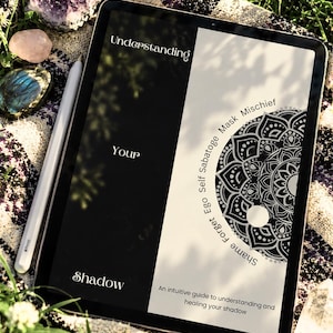 Op de afbeelding: Een digitale tablet met een zwart-wit hoes getiteld Understanding Your Shadow, met een cirkelvormig mandala-ontwerp en de tekst Shame Forget Ego Self Sabotage Mask Mischief en An intuitive guide to understanding and healing your shadow.