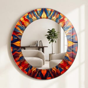 Puede incluir: Espejo redondo decorativo con un colorido diseño de vidrieras. El borde del espejo presenta un vibrante patrón de tonos rojos, naranjas, amarillos y azules. El espejo está colgado en una pared blanca, reflejando una habitación con muebles y una planta.