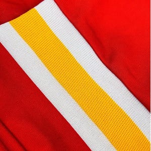 Peut inclure: Un v&ecirc;tement rouge vif pr&eacute;sentant un motif &agrave; rayures verticales pro&eacute;minent. La rayure se compose d'une bande centrale jaune flanqu&eacute;e de deux panneaux blancs &agrave; texture maill&eacute;e, cr&eacute;ant un contraste audacieux avec le tissu rouge uni.