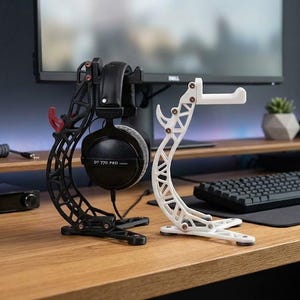 May include: Two 3D-printed headphone stands, one black and one white, featuring a lattice-like structural design with small red accents at the joints. The black stand holds a pair of black over-ear headphones labeled DT 770 PRO on the ear cup.