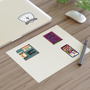 May include: A selection of stickers with blockchain-related designs. One sticker shows a shield with the text "Blockchain Developer" and "Master of Consensus." Other stickers include a floppy disk, a circuit board, and a smartphone.