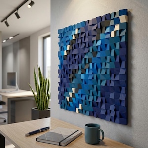 May include: A square wall art piece composed of numerous small, protruding wooden blocks in varying shades of blue, navy, black, and white. The blocks are arranged to create a textured, three-dimensional surface with a geometric pattern.