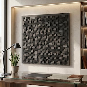 Op de afbeelding: Een vierkant wandkunstwerk bestaande uit talloze kleine, donker houtskoolkleurige houten blokjes die in een gestructureerd, driedimensionaal raster zijn gerangschikt. De individuele blokjes variëren in diepte en oriëntatie voor een complex oppervlak.