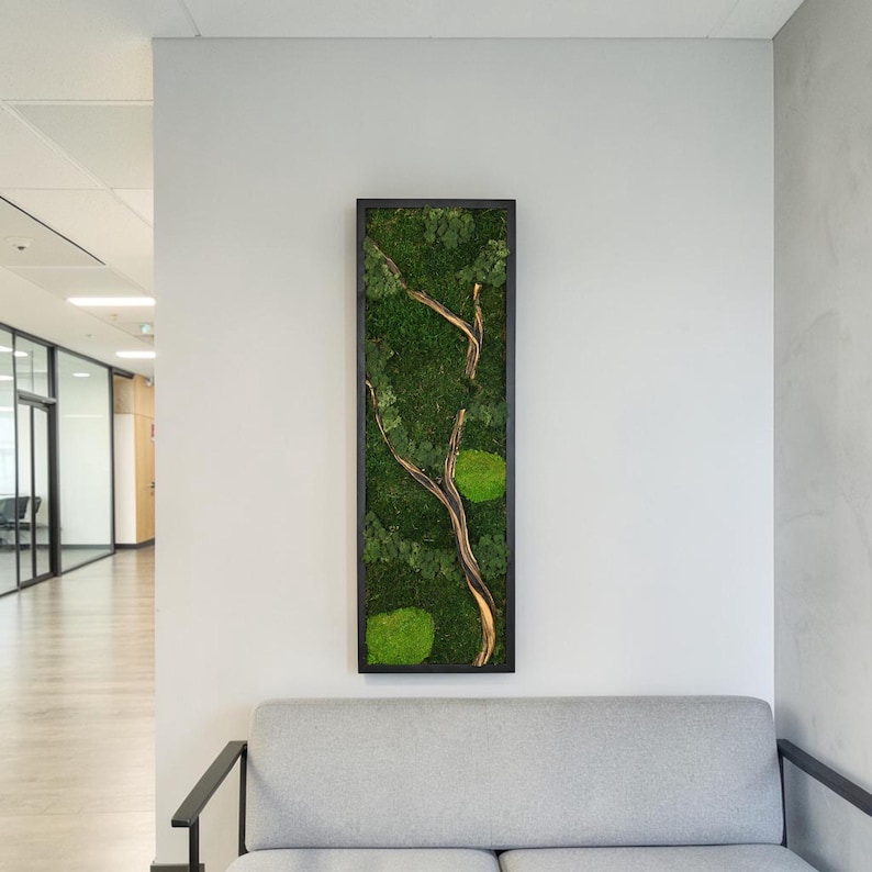 May include: A rectangular wall art piece featuring a black frame filled with preserved green moss and a central light brown wooden branch. The moss displays various shades of green, including deep forest tones and bright lime patches, arranged around the branch.