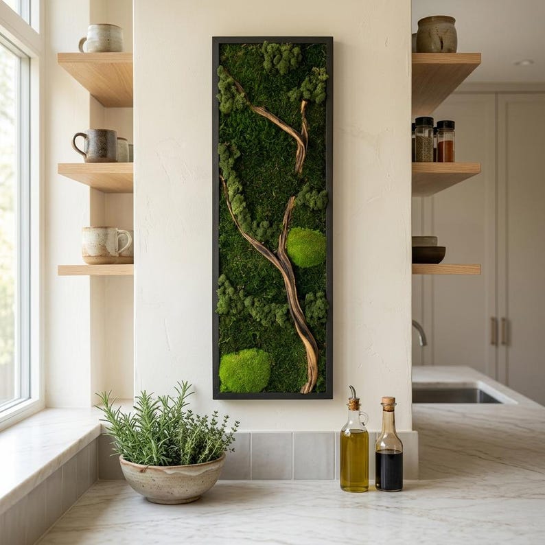 May include: A rectangular wall art piece featuring a black frame filled with preserved green moss and a central piece of light brown driftwood. The moss displays various shades of green, including deep forest tones and bright, rounded moss clusters.