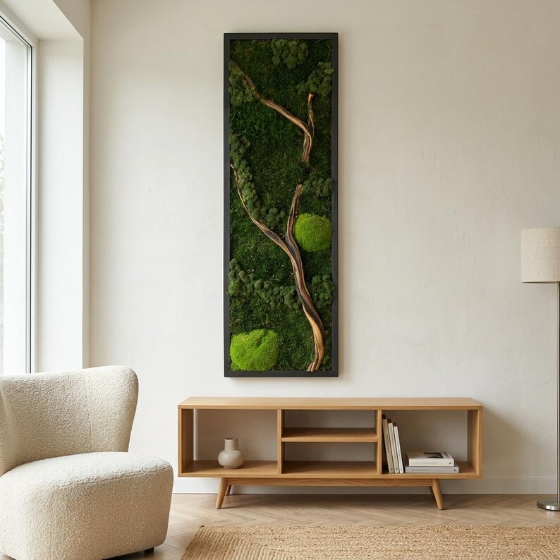 May include: A tall, rectangular wall art piece featuring a black frame filled with preserved green moss and a central, curved piece of light brown driftwood. The moss displays various shades of deep forest green and bright lime green textures.
