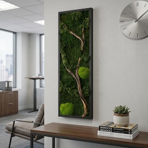 May include: A vertical rectangular wall art piece featuring preserved green moss and a natural wooden branch encased in a thin black frame. The composition includes textured dark green moss clusters and two bright green rounded moss mounds.