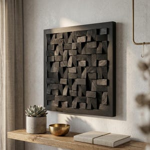 May include: A square, dark-stained wooden wall art piece with a three-dimensional design. The artwork is composed of various-sized wooden blocks arranged within a framed border. The blocks create a textured, abstract pattern. The piece is mounted on a light-colored wall.