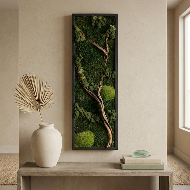 May include: A rectangular wall art piece featuring a black frame filled with deep green preserved moss and a central piece of light brown driftwood. The moss displays varied textures and shades of green, creating a dense, natural forest-like appearance.