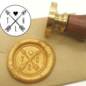 May include: A gold wax seal with a design of two crossed arrows with a heart in the centre. The arrows have the letters "T", "H", "L" on them. The seal is on a brown envelope.