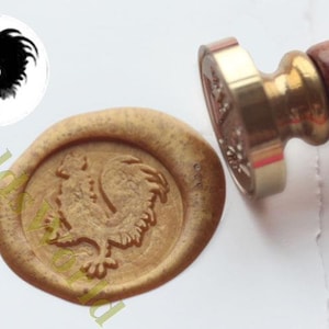 Peut inclure: Un sceau de cire doré avec un motif de coq. Le sceau est fait d'un tampon en métal avec une poignée en bois.