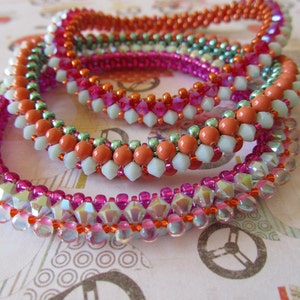May include: Four beaded bracelets stacked on top of each other. The bracelets are made with various colors of beads, including pink, orange, white, and green.