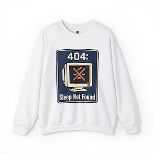 May include: White sweatshirt with a navy blue graphic that reads "404: Sleep Not Found." The design features a retro computer monitor with a crossed-out screen and the zzz symbol, representing sleep mode.