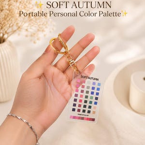 May include: A clear rectangular acrylic card featuring a grid of various color swatches labeled SOFT AUTUMN and MAKE UP COLOR, attached to a gold-toned metal keyring. The card displays multiple rows of small squares in shades of pink, blue, green, and brown.