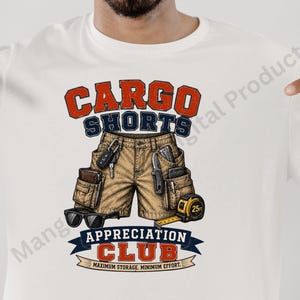 May include: A white t-shirt featuring a graphic of tan cargo shorts filled with items including keys, a pocket knife, a wallet, and a yellow 7.6m tape measure. The text reads CARGO SHORTS APPRECIATION CLUB and MAXIMUM STORAGE, MINIMUM EFFORT.