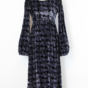 May include: Black velvet dress with a gray floral pattern. The long-sleeved dress has a round neckline and a gathered waist. The dress is displayed on a mannequin.