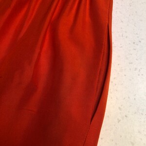 May include: Close-up of a rust-colored fabric with a seam running down the side.