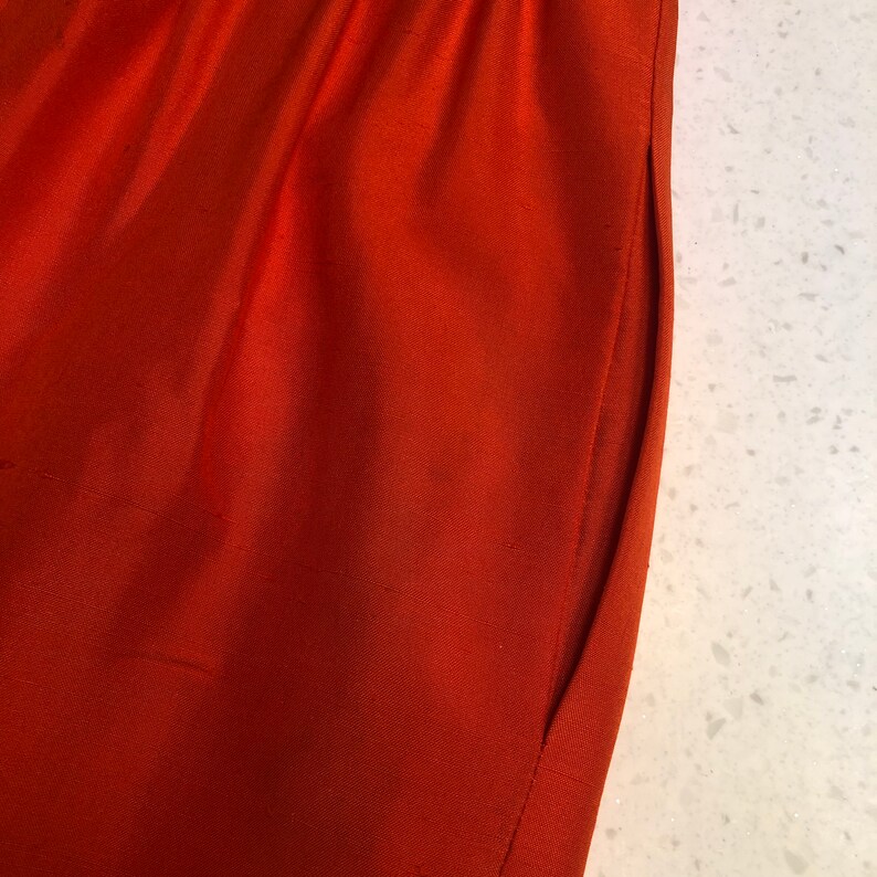 May include: Close-up of a rust-colored fabric with a seam running down the side.