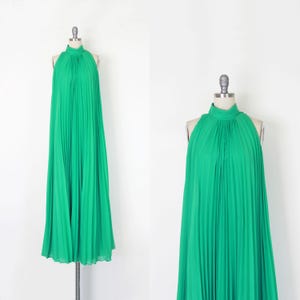 May include: A floor-length, vibrant green sleeveless dress featuring a high halter neckline and a fully pleated design. The garment hangs straight from the neck, creating a loose, flowing silhouette that extends down to the floor.