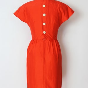 May include: A bright orange dress with short sleeves and a button-up back.