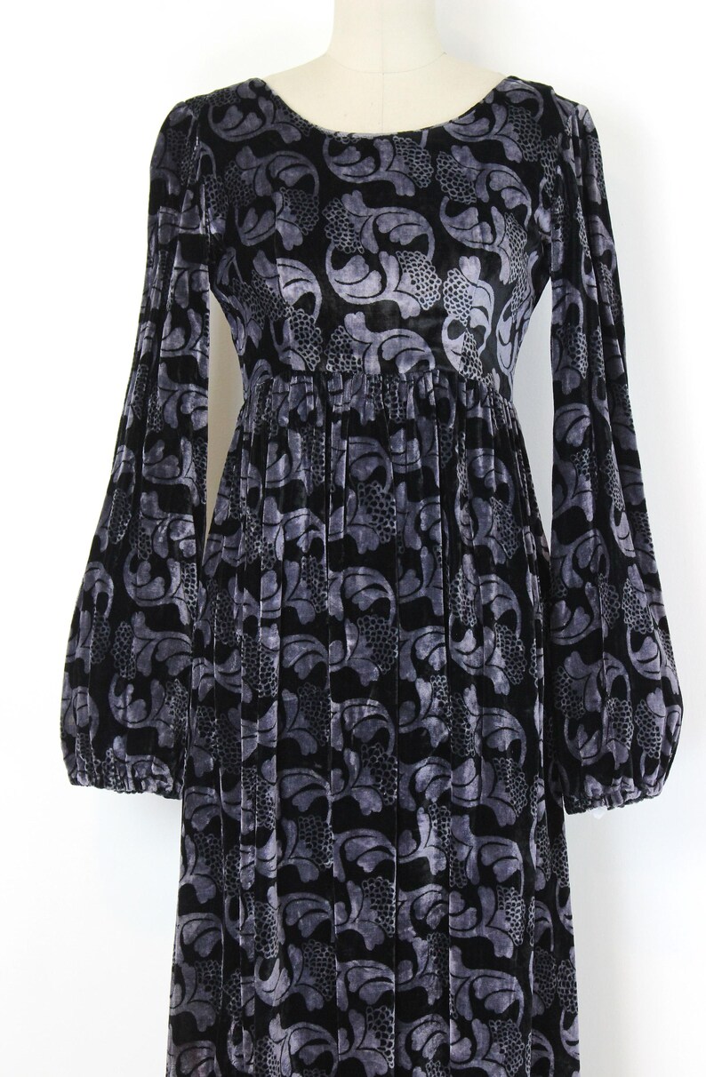 May include: Black and gray velvet dress with a floral pattern. The dress features long, voluminous sleeves and a gathered waist. The fabric has a soft, textured appearance, and the design is suitable for formal occasions.