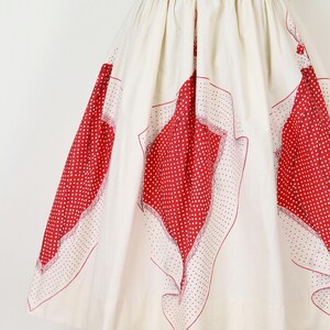 May include: A vintage-style skirt in cream fabric with large red polka dot patterns. The skirt features a high waist and a full, flowing silhouette. The red patterns are framed with a delicate white border.