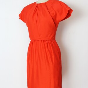 May include: A bright orange short-sleeved dress with a gathered neckline and a fitted silhouette.