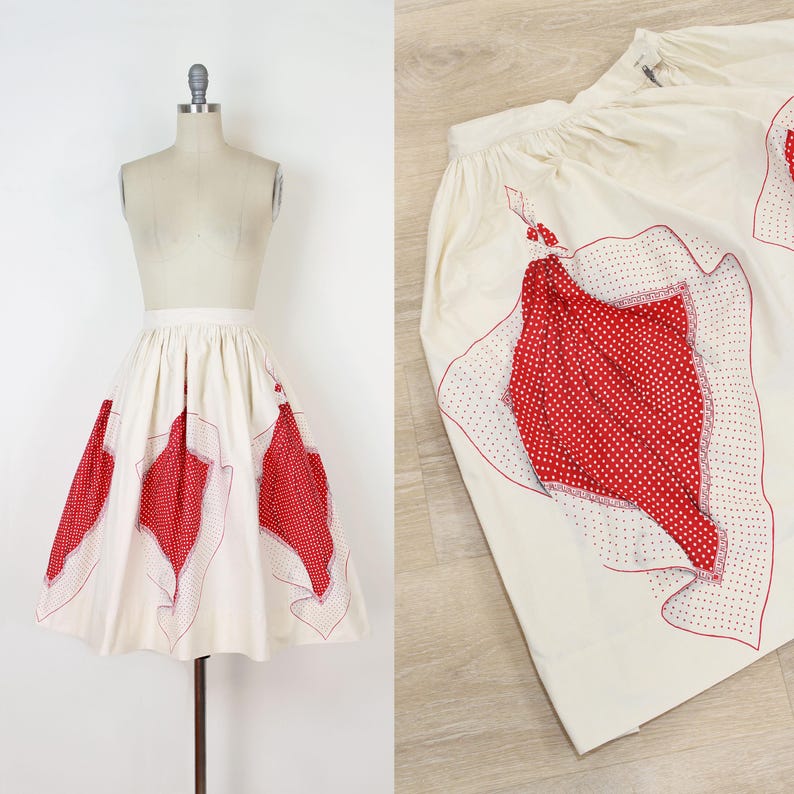 May include: Cream-colored skirt with red polka dot and solid red accents. The skirt features a high waist and a flared silhouette. The red accents are in a leaf-like shape and are outlined with red stitching. The skirt is displayed on a mannequin.