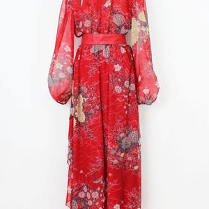 May include: A red maxi dress with a floral print and a matching red sash. The dress has long sleeves and a scoop neckline.