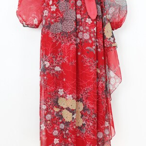 May include: A red maxi dress with a floral print and a ruffled hem. The dress has a V-neckline and long sleeves with a gathered detail at the shoulders. The dress is cinched at the waist with a matching red sash.