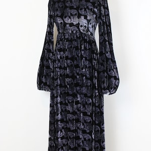 May include: A long, black velvet dress with a gray floral pattern. The dress features long, voluminous sleeves and a fitted bodice that flows into a full skirt. The dress is displayed on a mannequin against a white background.