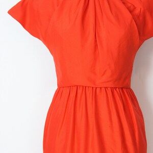 May include: A bright orange dress with a gathered neckline and short, cap sleeves. The dress has a fitted bodice and a flowing skirt.