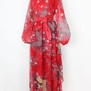 May include: A red maxi dress with a floral print and a matching red sash. The dress has long sleeves and a flowing skirt.