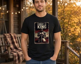 May include: A black short-sleeved t-shirt featuring a rectangular graphic print of a knight in armor kneeling with a sword. The text above the knight reads CHRIST IS KING in bold white letters against a dark, textured background.