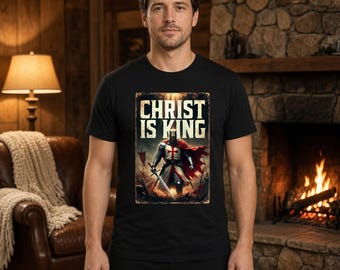 May include: A black short-sleeved t-shirt featuring a graphic print of a medieval knight in armor with a red cross on the chest, holding a sword. Above the knight, the text reads CHRIST IS KING in a bold, weathered, light-colored font.