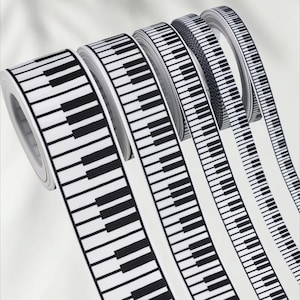 May include: A selection of ribbon rolls featuring a black and white piano key design. The ribbon is wound tightly, with the piano key pattern repeating along its length. The contrasting black and white creates a striking visual. Suitable for crafting and music-themed projects.