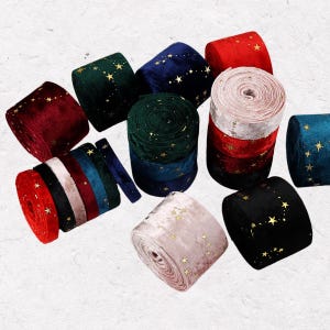 May include: An assortment of velvet ribbon rolls in various colors, including red, green, blue, and black. Each roll is adorned with gold star patterns. The ribbons are suitable for crafts and gift wrapping.