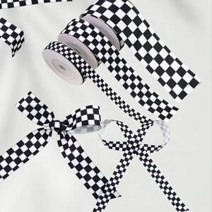 May include: Black and white checkered ribbon rolls and bows. The ribbon is arranged on a white surface. The ribbon is in various stages of being unrolled, with some pieces formed into bows. The pattern is a classic checkerboard design.