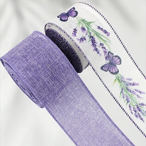 Puede incluir: Dos rollos de cinta decorativa. Uno es de color lavanda liso, el otro es blanco con un diseño floral y de mariposas en lavanda. Los bordes de la cinta blanca están ribeteados con una puntada morada oscura.