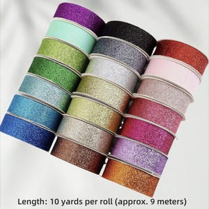 May include: A selection of glitter ribbon rolls in a range of colours, such as purple, green, blue, silver, gold, pink, and red. Each roll is approximately 9 metres long. The ribbon has a shiny, textured finish.