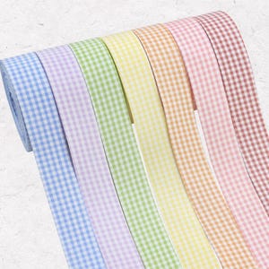 Könnte beinhalten: Eine Rolle mehrfarbigen Vichy-Bands in Blau-, Lila-, Grün-, Gelb-, Orange-, Rosa- und Rottönen. Das Band hat ein klassisches Karomuster. Ideal für Bastelarbeiten, Geschenkverpackungen und andere dekorative Projekte.