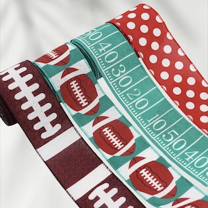Pode incluir: Várias fitas decorativas com desenhos temáticos de futebol americano. Uma fita apresenta um padrão de campo de futebol, outra tem bolas de futebol vermelhas, uma terceira tem atacadores de futebol brancos sobre um fundo bordô e a última tem bolinhas vermelhas.